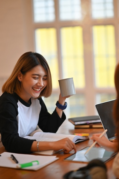 Young asian woman tutoring friend on wood table.