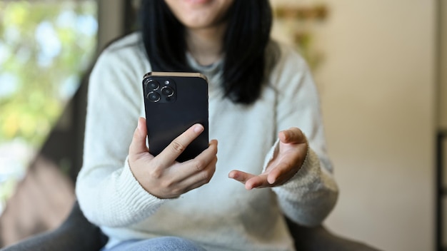 A young Asian woman using her smartphone cropped image