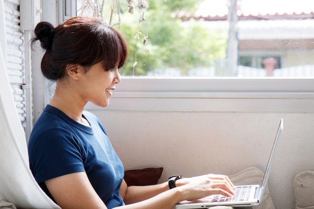 Giovane donna asiatica che utilizza il taccuino del computer portatile alla caffetteria. concetto di e-learning - immagine.