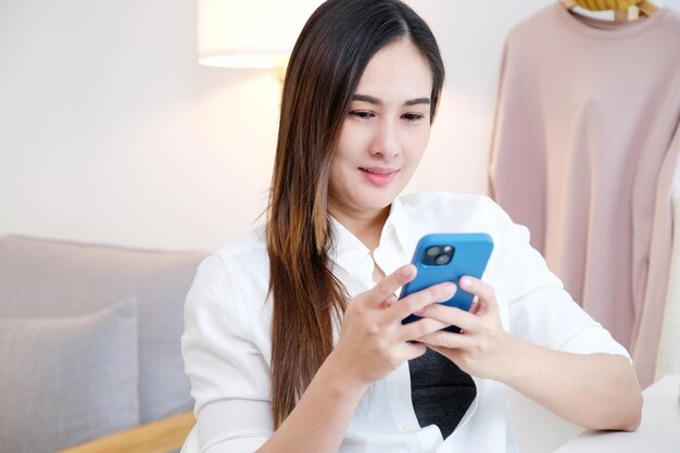 Young asian woman using phone with smiling happy and relax emotion at home