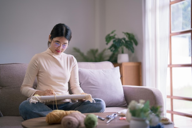 Young asian woman using punch needle to embroidery on fabric for craft handmade in hobby lifestyle