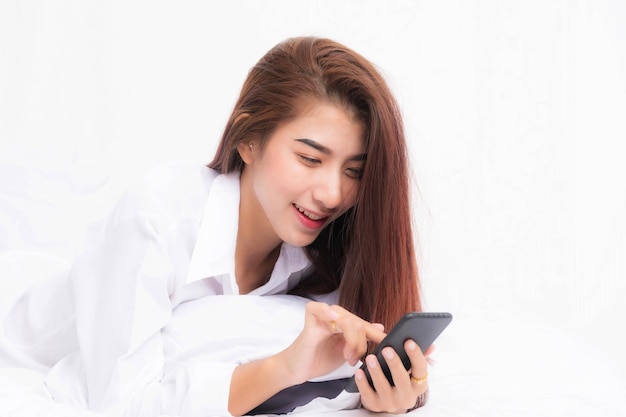 Young Asian woman using smart phone in bedroom at home happy and smile.