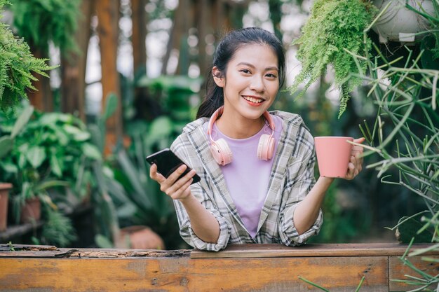 庭でスマートフォンを使用して若いアジアの女性