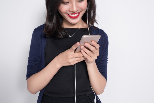 흰색으로 격리된 스마트폰을 사용하는 젊은 아시아 여성.
