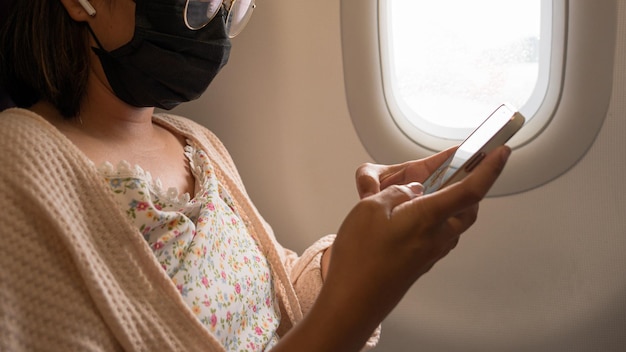 写真 飛行機の技術とビジネスコンセプトの背景にスマートフォンの白い画面を使用して若いアジアの女性