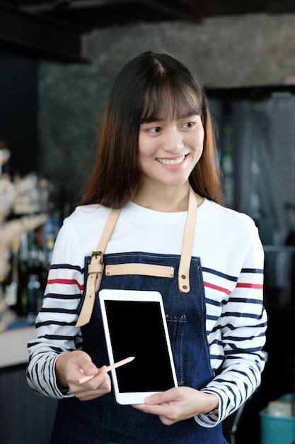 Young asian woman using tablet at cafe counter background