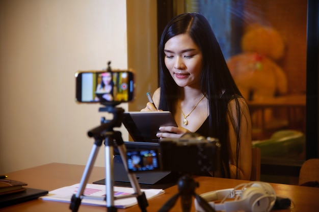 Young asian woman vlogger recording video content for online channelfemale looking at camera and talking on video shootingcontent creator maker or social influencer  concept