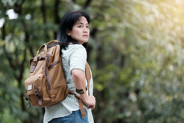 Photo young asian woman walking in green tree nature background