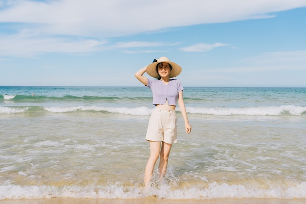 열 대 해변에서 산책하는 젊은 아시아 여성