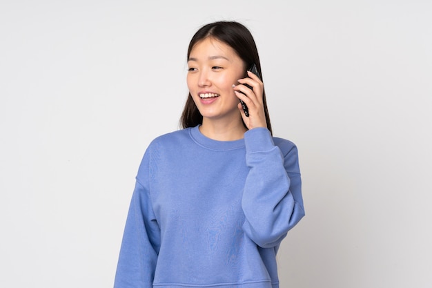 Young asian woman on wall keeping a conversation with the mobile phone