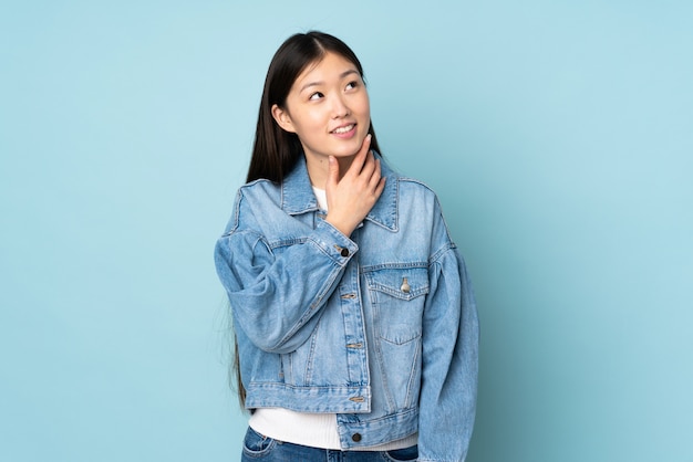 Young asian woman on wall looking up while smiling