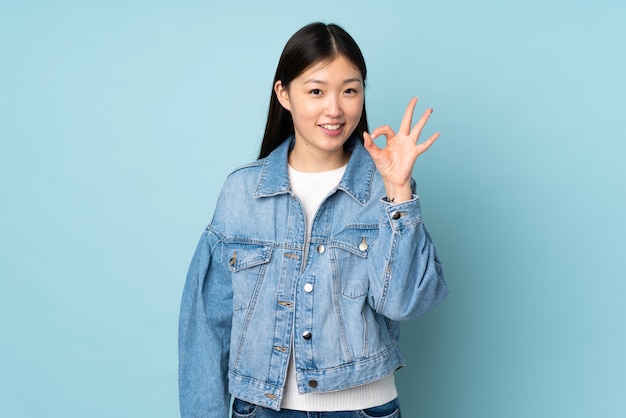 Young asian woman on wall showing ok sign with fingers