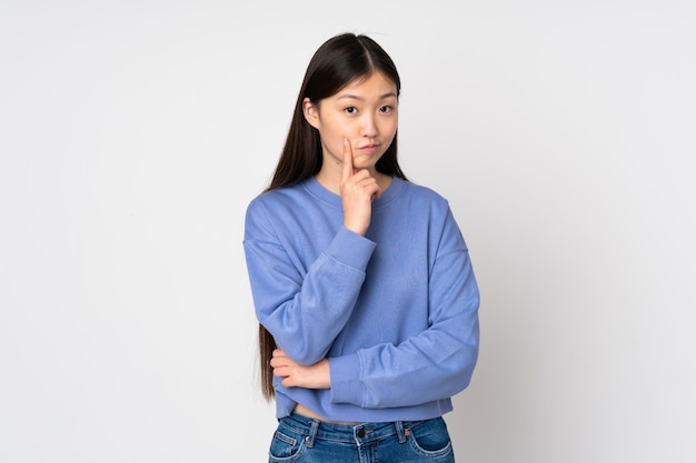 Young asian woman on wall and thinking