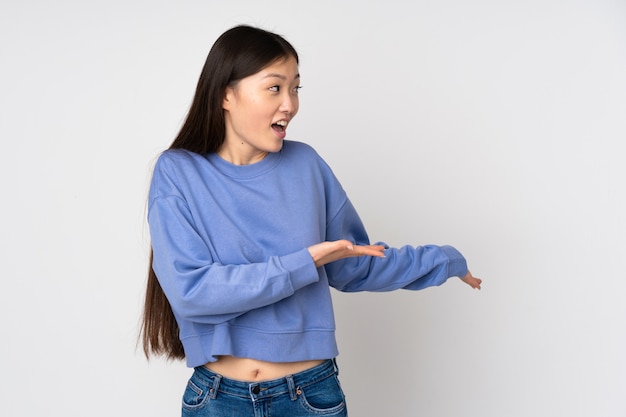 Young asian woman on wall with surprise expression while looking side