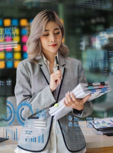 Giovane donna asiatica che guarda l'interfaccia innovativa tecnologia aziendale sugli schermi ai digitali