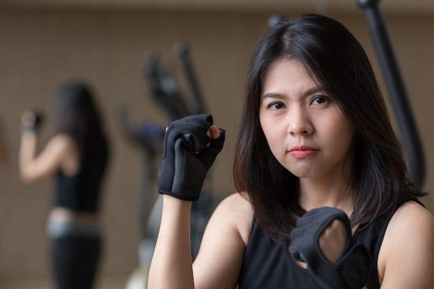 Young asian woman wear gloves workout in gym