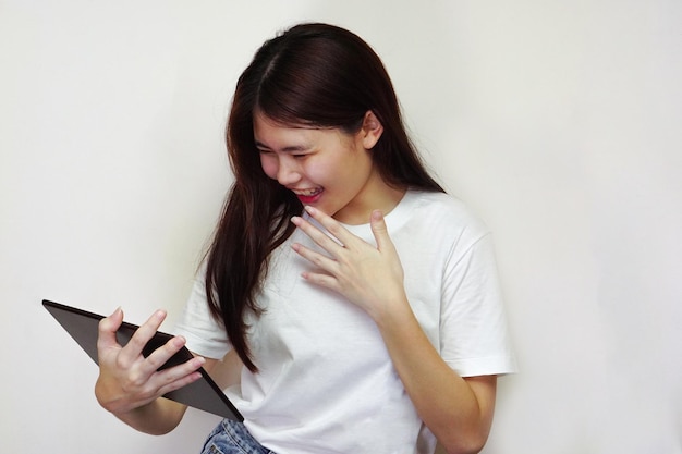 The young asian woman wear white tshirt using a tablet happily