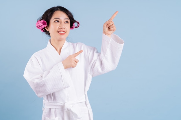 Young Asian woman wearing bathrobe on blue background