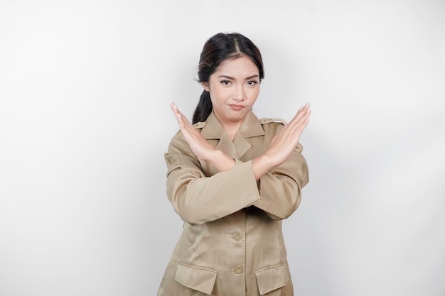 Young asian woman wearing a brown uniform shows crossed hands or stop gesture isolated white background