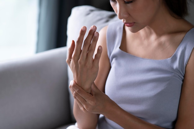 Young Asian woman wearing casual clothes suffering pain on hands and fingers arthritis inflammation Woman has pain in wrist Health care and medical concept