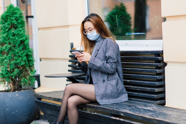 Young asian woman wearing face mask is standing at a domestic street. New normal covid-19 epidemic