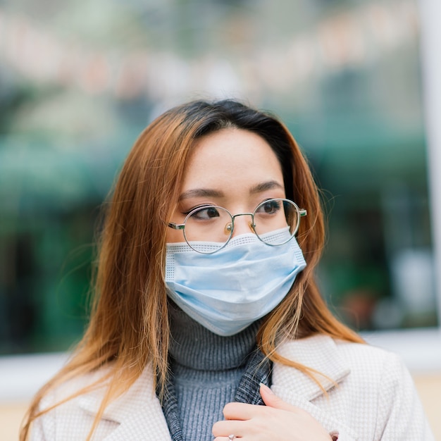 Young asian woman wearing face mask standing at a domestic street 