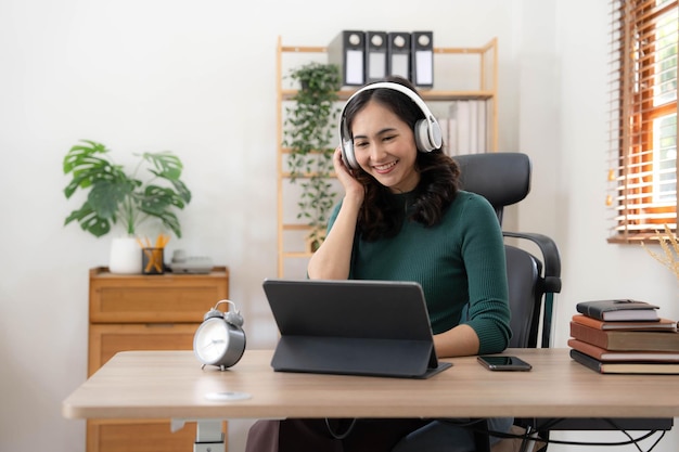 Young Asian woman wearing headphones to study online with her teacher the girl is happy to learn