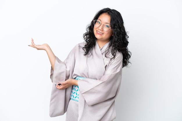 Young asian woman wearing kimono isolated on white background extending hands to the side for inviting to come