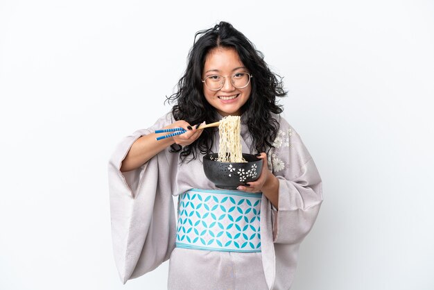 Young asian woman wearing kimono isolated on white background holding a bowl of noodles with chopsticks