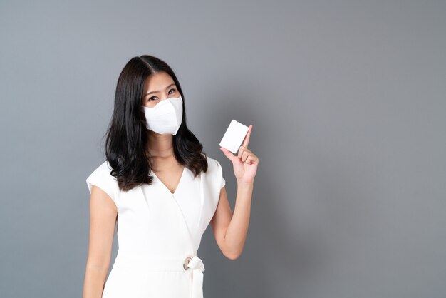 Giovane donna asiatica che indossa una maschera e utilizzando alcol spray a portata di mano per proteggere il virus corona