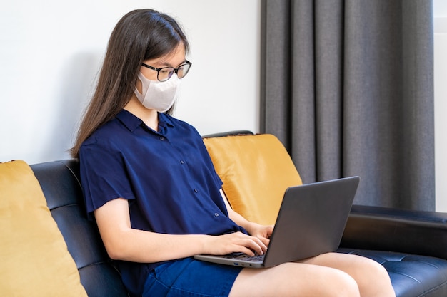 Young Asian woman wearing N95 mask, working from home