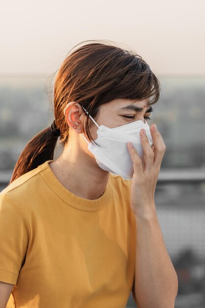 young asian woman wearing n95 respiratory mask protect and filter pm25 or particulate matter against bad air pollution in city air quality index aqi unhealthy healthcare concept