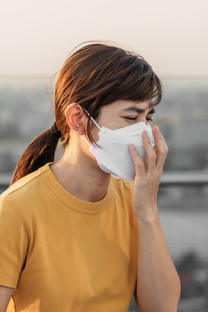 N95 呼吸マスクを身に着けている若いアジア女性は、都市大気質指数 AQI の悪い大気汚染に対して pm25 または粒子状物質を保護し、フィルター処理します。不健康なヘルスケアの概念