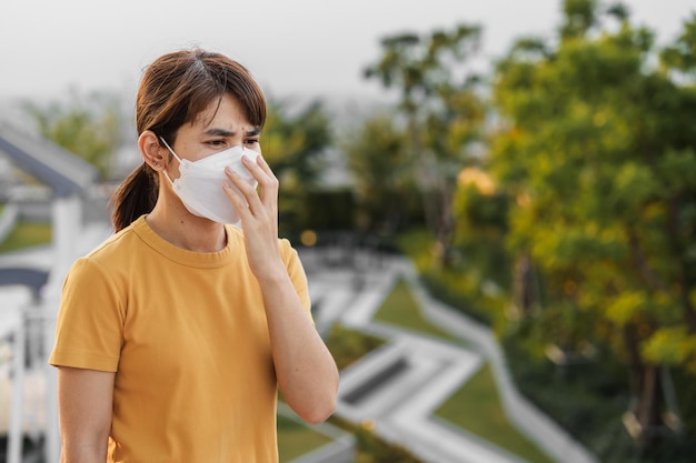 N95 호흡 마스크를 착용한 젊은 아시아 여성은 도시 대기질 지수 AQI 건강에 해로운 건강 관리 개념에서 나쁜 대기 오염에 대해 pm25 또는 미립자 물질을 보호하고 필터링합니다.