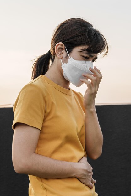 Giovane donna asiatica che indossa la maschera respiratoria n95 protegge e filtra il pm25 o il particolato contro il cattivo inquinamento atmosferico nell'indice di qualità dell'aria della città aqi concetto di assistenza sanitaria malsana