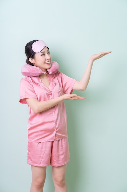 Young Asian woman wearing pajamas on green background