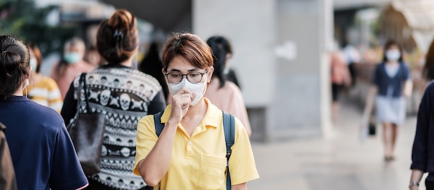 公共の駅で新規コロナウイルス（2019-nCoV）または武漢コロナウイルスに対する保護マスクを身に着けている若いアジア女性は、呼吸器感染症を引き起こす伝染性ウイルスです。