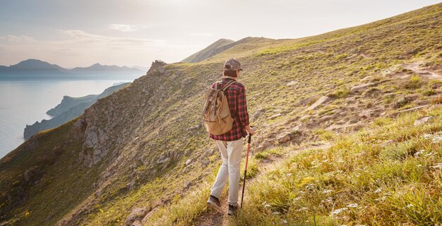 A young Asian woman with a backpack hiking in the summer