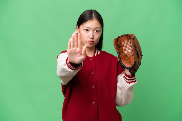 Photo young asian woman with baseball glove over isolated background making stop gesture