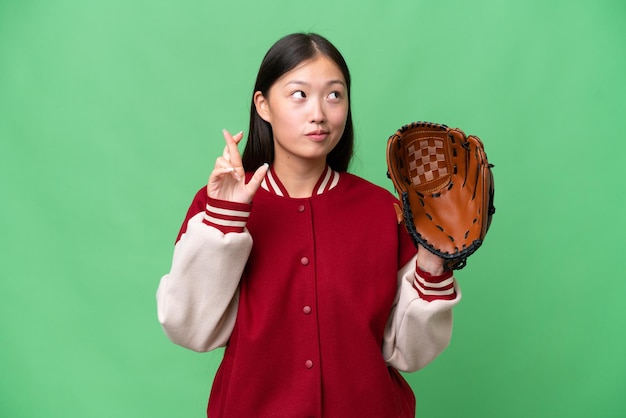 Young asian woman with baseball glove over isolated background with fingers crossing and wishing the best