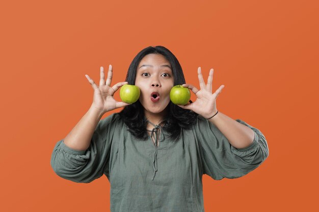 Young asian woman with beautiful smile holding fresh green apple, promoting healthy nutrition