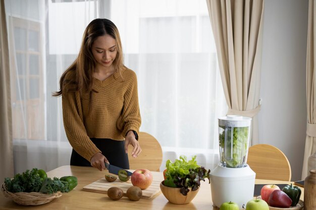 ブレンダーと自宅でデトックススムージーを作る若いアジアの女性健康的な食事の概念