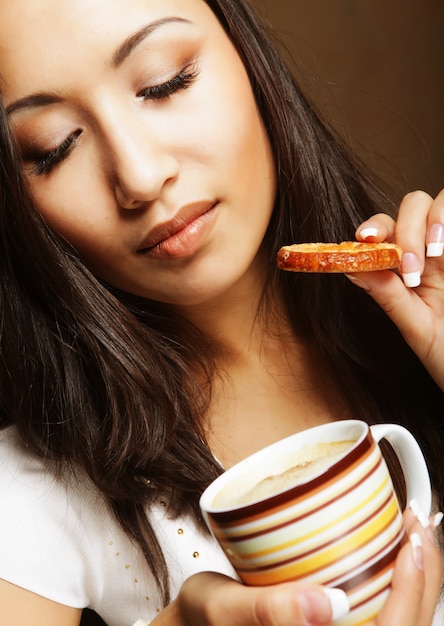 Giovane donna asiatica con caffè e biscotti.