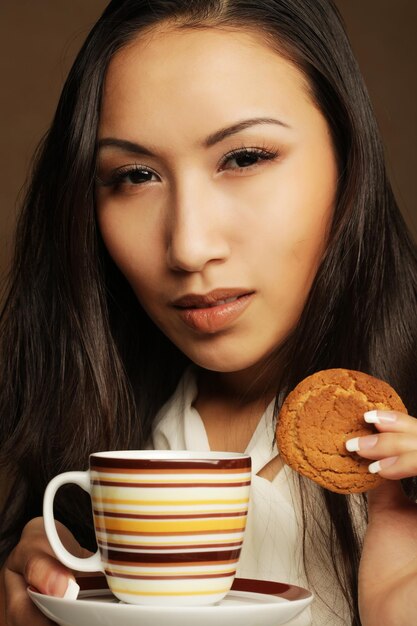 Giovane donna asiatica con caffè e biscotti.