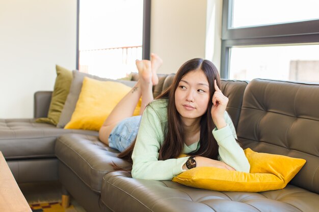 Young asian woman with a concentrated look, wondering with a doubtful expression