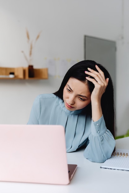 Foto giovane donna asiatica con espressione frustrata mentre lavora con il computer, lavora da casa, casual