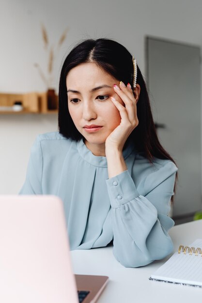 Foto giovane donna asiatica con espressione frustrata mentre lavora con il computer, lavora da casa, casual