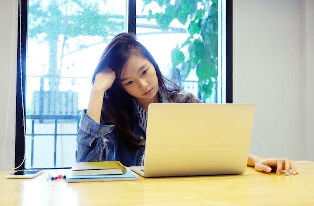 Young asian woman with frustrated expression while working with laptop computer