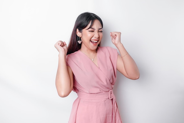 Photo a young asian woman with a happy successful expression wearing pink blouse isolated by white background