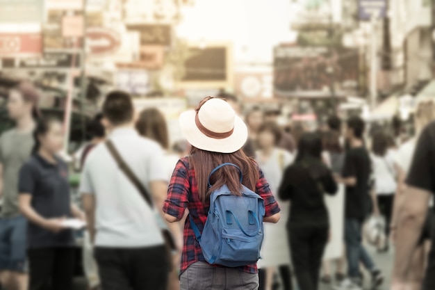 모자와 배낭 사람들 사이 시장에서 여행하는 젊은 아시아 여성